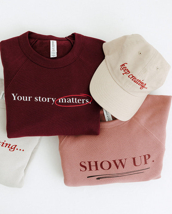 Maroon sweatshirt, beige cap, and pink crop top with motivational text on a white background